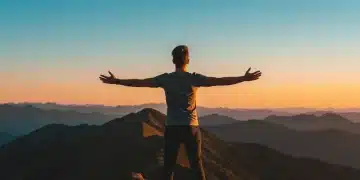 Person on mountain peak at sunrise, symbolizing self-esteem and success.