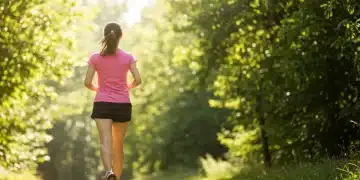Person jogging in a park, smiling, symbolizing improved mental health from exercise.